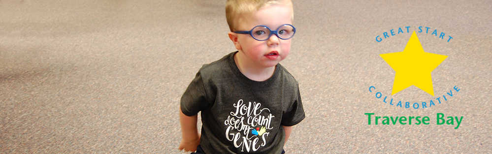 Toddler smiling. T-shirt says Love doesn't Count Genes.