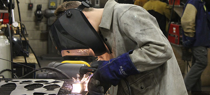 One student welder working with a torch and metal object.