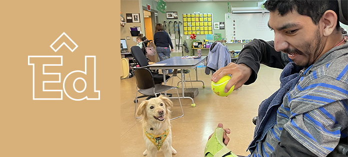 Smiling student throwing a ball to a service dog