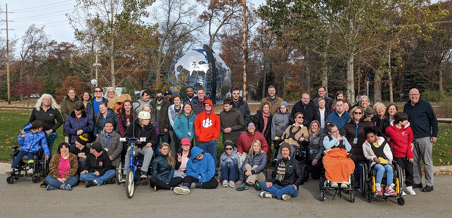 Photo of students and staff members of all abilities in a group outdoors.