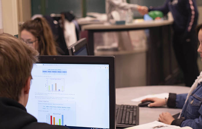 A male high school student analyzing data on a computer