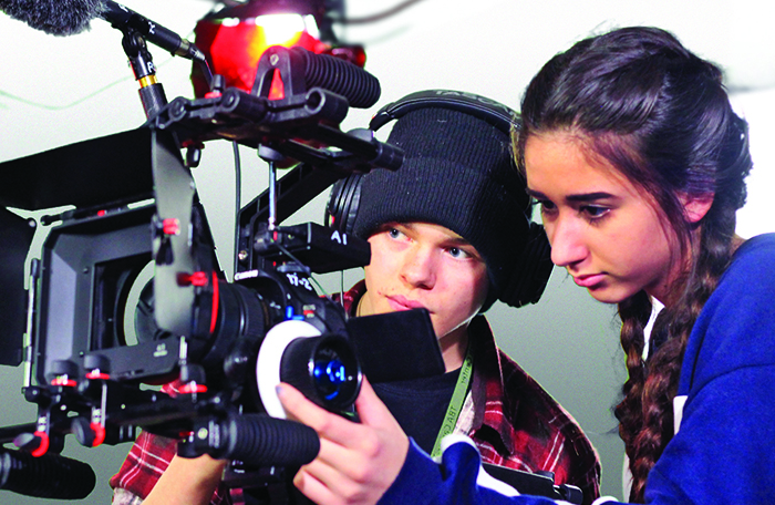 high school age boy and girl work with camera and lighting equipment.