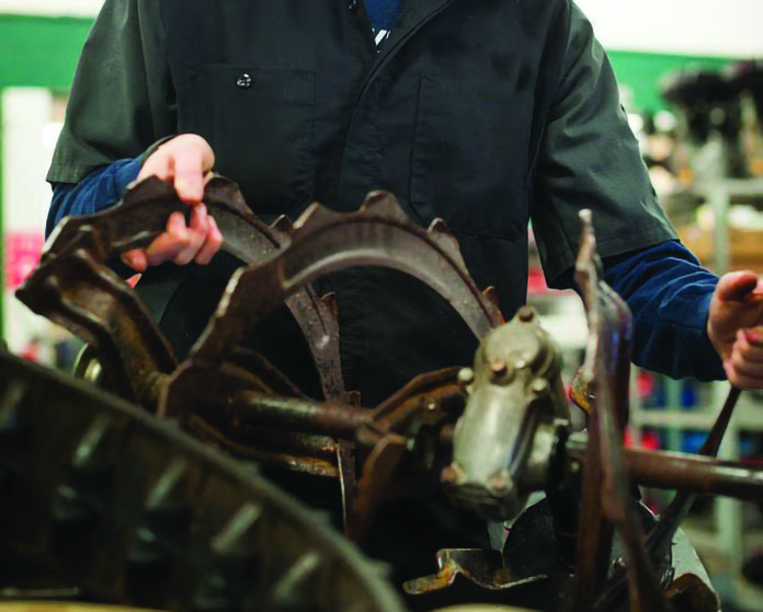 student working on gears and blades of lawn equipment